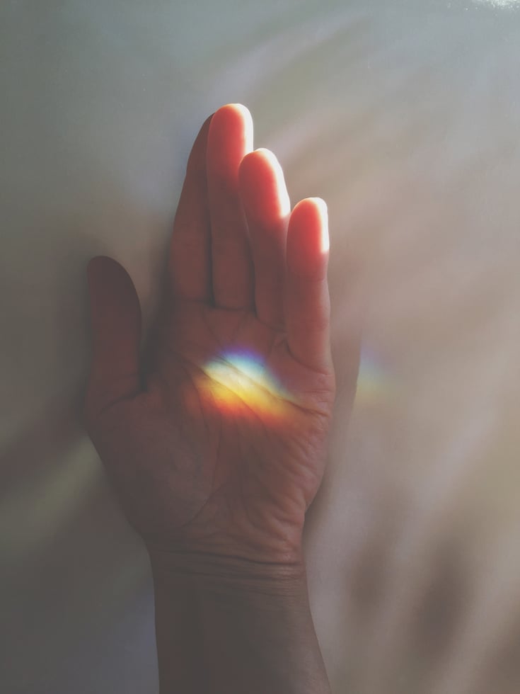 Poetic hand with a rainbow light